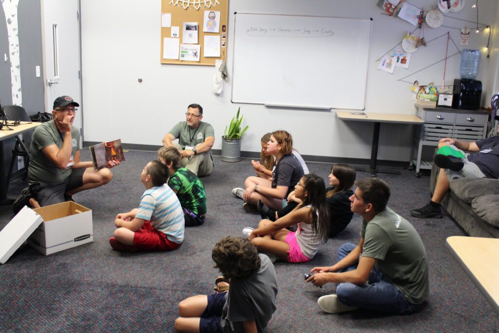 Students sit on the floor listening to a lesson