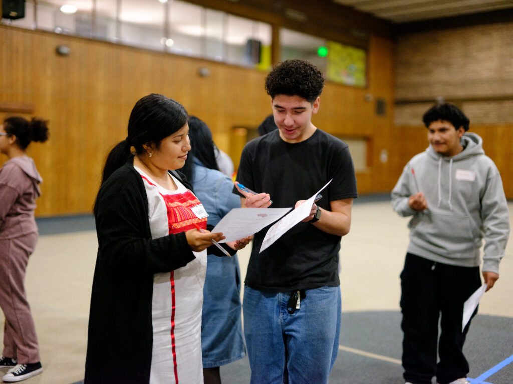Two students compare pieces of paper