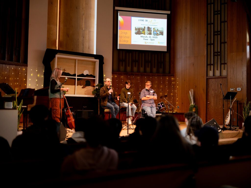 Three people sit on a stage talking