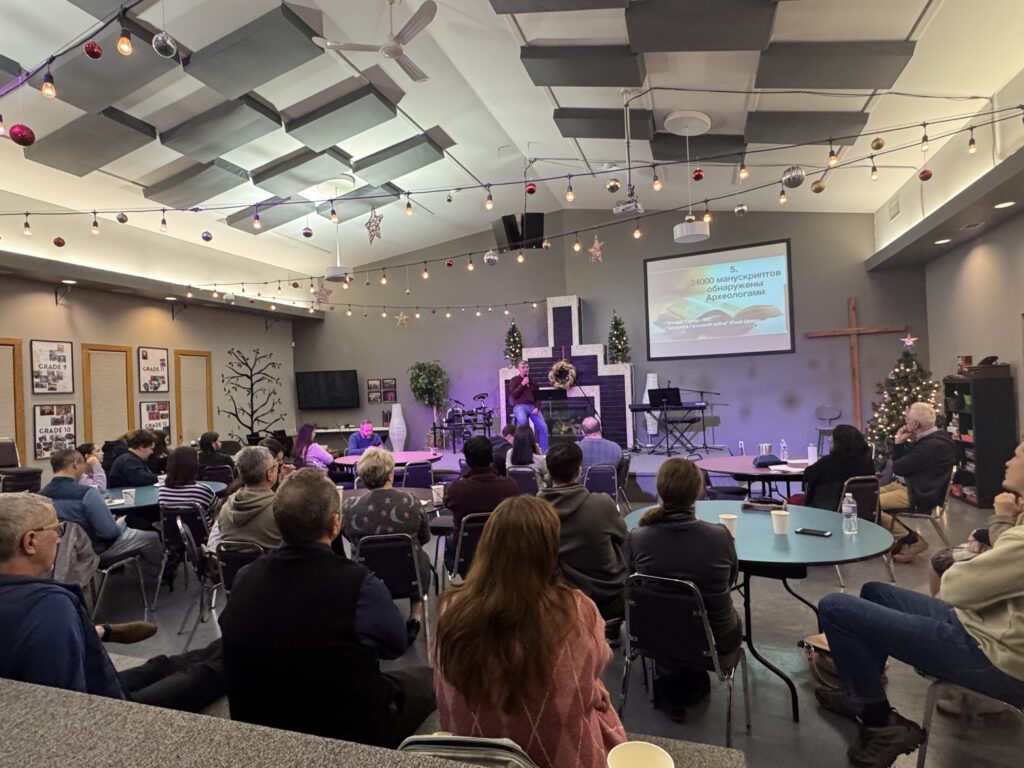 People sit at tables listening to a presentation.