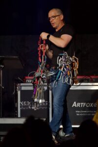 A speaker illustrates the "Anchored" theme by wearing rock climbing anchors