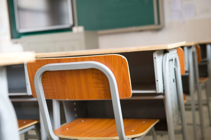 Empty classroom with chairs, desks and chalkboard.