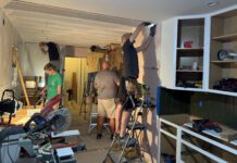 A surprise makeover Team of five works on cabinets and kitchen surfaces in construction setting.