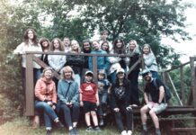 Lietuvos Laisvųjų Krikščionių Bažnyčia (Free Christian Church in Lithuania) Group of students and camp counselors stand and sit outdoors around a wooden platform.