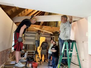 Six men doing construction work in a kitchen.