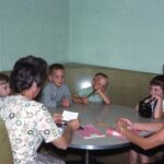 Children sitting in booth with two female teachers.