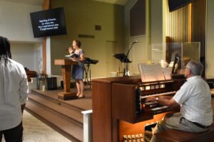 Woman singing at podium while organist plays.