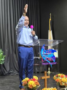 Man stands with arm extended, holding microphone.