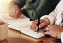MB Foundation highlights estate planning during national awareness week Bible, couple and hands writing of woman by table.