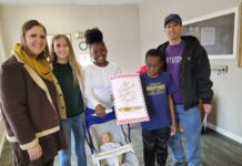A puzzle with purpose Family stands with toy baby after successfully solving escape room.