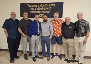 Seven men stand in a line.