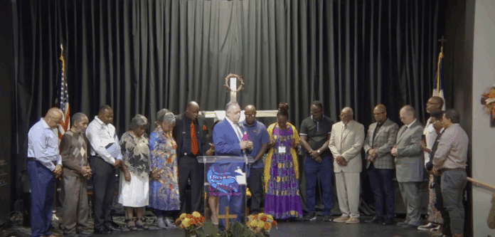 Prayer for pastors Standing in semi-circle with bowed heads.