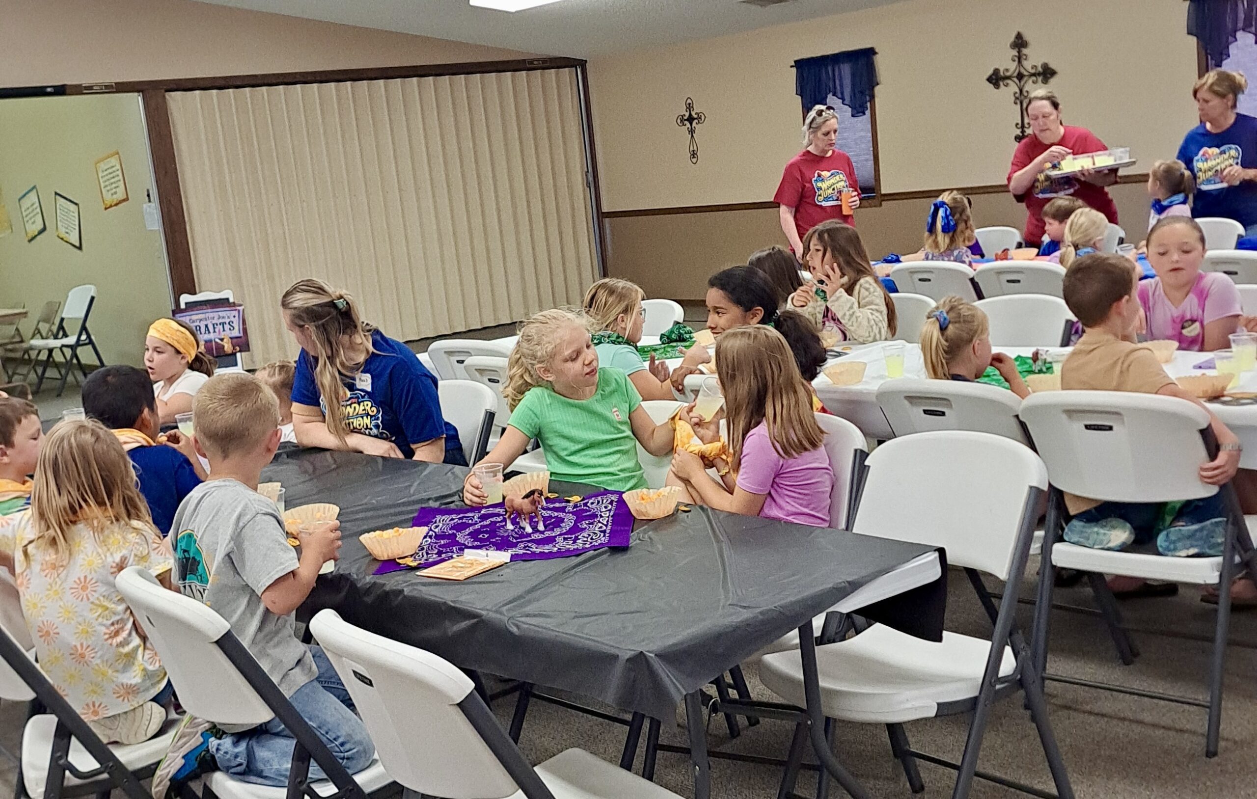 Children eating snacks at long tables. 