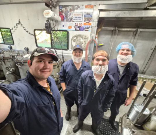 MCC meat canners start season with memories from Malawi Four men in coveralls and hair and beard nets.